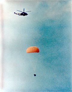 Gemini XII Splashdown on November, 11, 1966: As a helicopter hovers above, the Gemini XII spacecraft with parachute open descends to the Atlantic with astronauts Jim Lovell and Edwin Buzz Aldrin aboard.