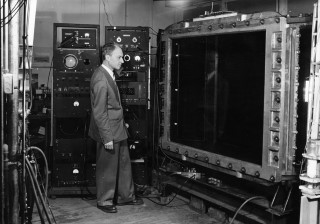 Bruno Rossi: Bruno Rossi standing before the multiplate cloud chamber used by his Cosmic Ray Group at MIT, 1954.