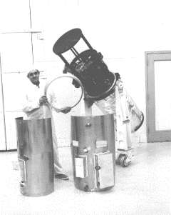 IUE Spectrograph Assembly: A technician displays the shroud and support rings used to cover the spectrograph assembly, raised above the telescope tube. The tube has been partially covered with mylar thermal insulation, and the sunshade has been removed.