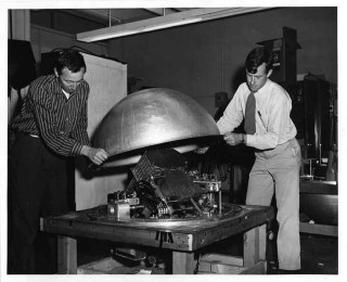 Kraushaar and Clark: Professors William Kraushaar and George Clark close the air-tight cover on the balloon gondola that carried the second of their two (unsuccessful) balloon experiments in search for high-energy cosmic gamma rays.